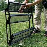 Setting up a black camping chair on grass