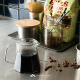 Coffee-making setup with a pitcher of coffee, coffee beans, and a bag of Hills Bros Coffee on a kitchen counter.