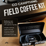 Go Campthing Field Coffee Kit shown open on a wooden surface, with a black soft tray holding a small black insulated bottle and a black hard case in the background. White text on the case reads 'GO CAMPTTHING FIELD COFFEE KIT' and 'BREW OUTSIDE'.